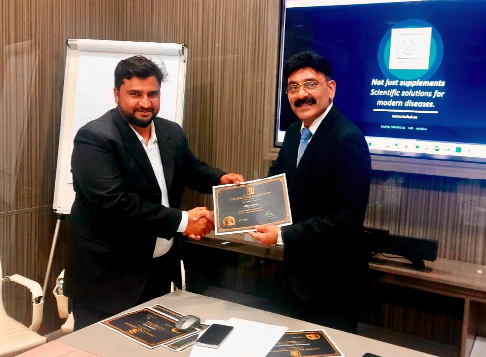 Mohammed Shakeel Hashmi shaking hands with a partner over a certificate at the RAUFSAL office